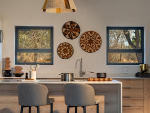 侯斯普瑞特Nomads Den Luxury Villa with Riverbed View的厨房设有两扇窗户和一个带椅子的柜台。