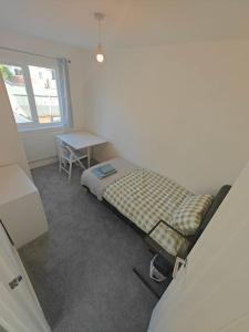 南安普敦Stunning 4 bed House Ideal for Contractors的一间卧室配有一张床、一张桌子和一个窗户。