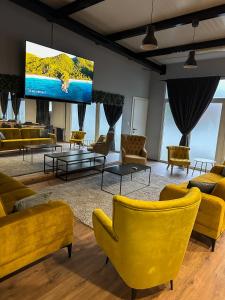 奥西耶克XXL rooms&spa的客厅配有黄色椅子和平面电视