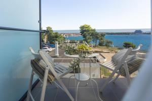 沃迪切Villa Arausa的俯瞰水面的阳台配有两把椅子和一张桌子