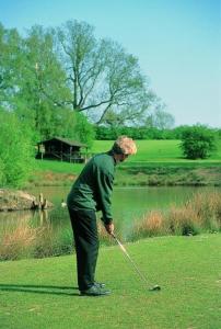 温彻斯特马维尔预定酒店的一个人在湖边打高尔夫球