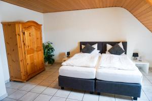 WeilerbachHotel zur Schlemmerscheune的一间卧室设有两张床和木制橱柜