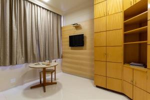 乌贝拉巴UBERABA APART HOTEL的客房设有桌子、电视和橱柜。