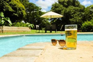 利隆圭Kumbali Country Lodge的一杯啤酒和一双太阳镜,在游泳池边
