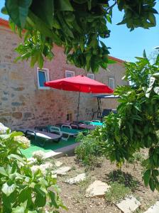 OuzendaCasa Virginia的一个带红色遮阳伞和躺椅的庭院