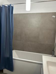 雷希察City Center Accommodation - 308的浴室设有白色浴缸和蓝色的淋浴帘