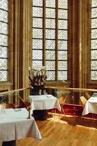 马斯特里赫特Kruisherenhotel Maastricht - Oostwegel Collection, member of Design Hotels的用餐室设有两张桌子和彩色玻璃窗