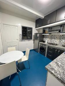 卡萨布兰卡L'Appartement Harmonia Cozy的厨房铺有蓝色的地板,配有白色的桌椅。