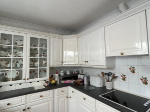 FeockCurlews的厨房配有白色橱柜和黑色台面