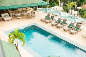 布卢梅瑙Villa do Vale Boutique Hotel的享有带椅子和遮阳伞的游泳池的上方景色