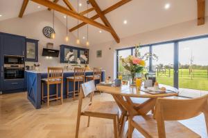 伊普斯威奇Large immaculate rural conversion - The Milking Parlour的厨房以及带木桌和椅子的用餐室。