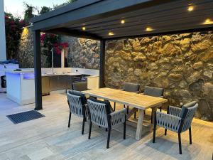 博德鲁姆Villa Aylinda with private heated Pool的庭院设有木桌、椅子和石墙