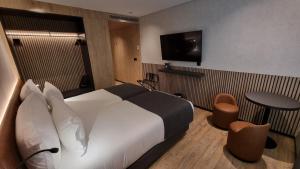 里斯本Hotel Principe Avila的一间酒店客房,配有一张床铺、一张桌子和一台电视