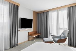 比尔Courtyard by Marriott Biel Bienne的酒店客房带一张床、一台电视和一把椅子