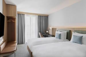 比尔Courtyard by Marriott Biel Bienne的酒店客房设有两张床和电视。