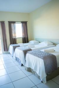 巴纳伊巴Pousada Aeroporto的酒店客房设有三张床和窗户。