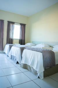 巴纳伊巴Pousada Aeroporto的白色和灰色的客房内的两张床