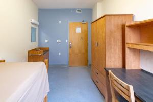 哈利法克斯戴尔豪斯大学旅舍的一间卧室配有一张床和一个木制橱柜