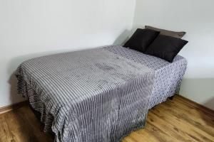 波苏斯-迪卡尔达斯Casa Única e Moderna Centro的一张带灰色毯子和黑色枕头的床