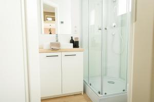 莱奇根Tiny Om Ferienhaus的带淋浴和盥洗盆的白色浴室