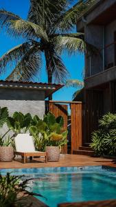 费尔南多 - 迪诺罗尼亚Vila Sal Boutique Noronha的一个带椅子和棕榈树的游泳池