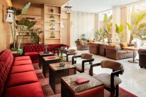 里斯本Avani Avenida Liberdade Lisbon Hotel的大堂设有红色的长沙发、桌子和植物