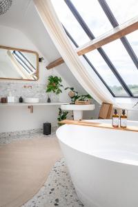 LeschesLA GRANDE MAISON LGM的带窗户的客房内设有带大型白色浴缸的浴室