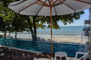 弗洛里亚诺波利斯Mighil Hotel & Eventos的海滩旁的游泳池配有遮阳伞和椅子