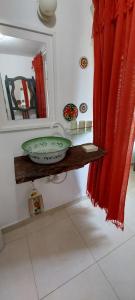 大坎普Recanto da Poesia的浴室设有水槽、镜子和红色窗帘