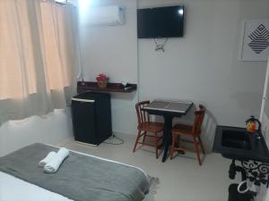 萨夸雷马SUITES VISTA MAR AZUL的配有床、桌子和电视的房间