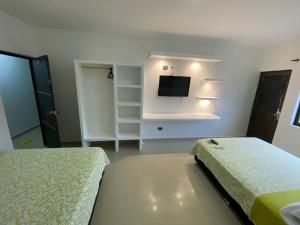 MitúHotel Los Paisas的一间卧室配有两张床和一台平面电视
