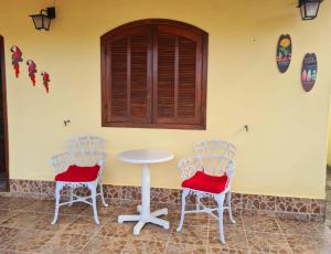 阿拉鲁阿马Casa em Condomínio com Piscina Privativa的墙上的房间里摆放着两把椅子和一张桌子