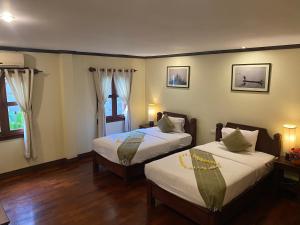 琅勃拉邦Luang Prabang Residence & Travel的客房内设有两张床,铺有木地板,设有窗户。