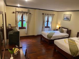 琅勃拉邦Luang Prabang Residence & Travel的酒店客房设有两张床和电视。