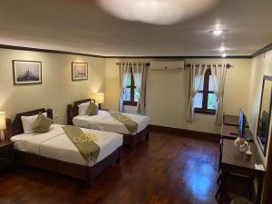 琅勃拉邦Luang Prabang Residence & Travel的酒店客房设有两张床和电视。
