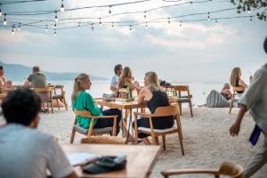 吉利阿尔Mowies Gili Air的一群坐在海滩桌子上的人