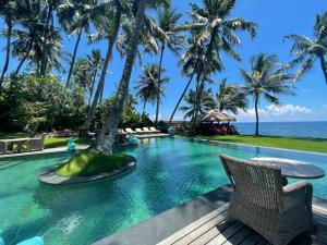 提安亚尔Louka Beach Bali的棕榈树和海洋度假村的游泳池