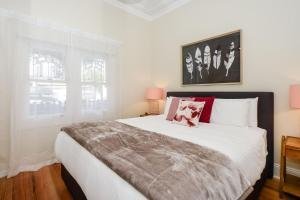 墨尔本Boutique Stays - Carlton Terrace的卧室配有带红色枕头的大型白色床