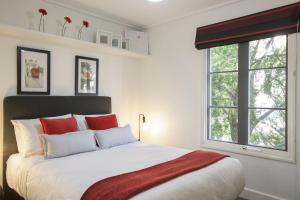墨尔本Boutique Stays - Wellington Mews的白色卧室配有一张带红色枕头的大床