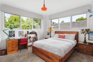 Mount WaverleyBoutique Stays - That 70s House的卧室配有一张床、一张书桌和窗户。