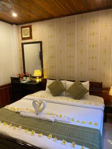琅勃拉邦金莲花广场宾馆的一间卧室配有一张带两个天鹅的床
