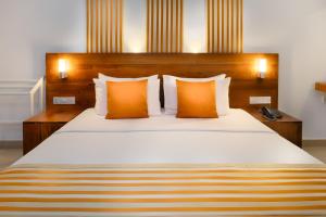 尼甘布卡米洛特海滩酒店的一间卧室配有一张带橙色枕头的大床