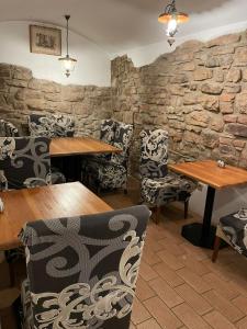 纳霍德Hotel U města Prahy Náchod的一间设有木桌和椅子的餐厅以及石墙