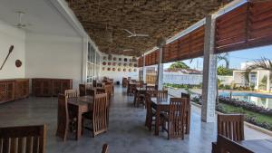 基林多尼Mafia Dream Hotel的一间带木桌和椅子的餐厅以及游泳池