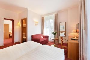 洛桑精英酒店的酒店客房配有一张床、一把椅子和一张书桌
