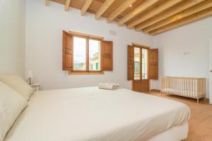 阿尔盖达Can Serral的白色卧室设有大床和窗户