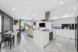 黄金海岸Luxury Modern Waterfront House的厨房配有白色橱柜和桌椅
