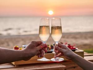 富国Crowne Plaza Phu Quoc Starbay, an IHG Hotel的两人在海滩的桌子上戴香槟杯
