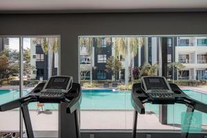 怡保Jomstay Manhattan Suites Ipoh Water Park Homestay的健身房享有游泳池的景致,设有2个跑步机