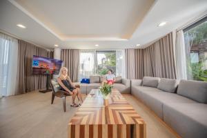 芽庄Nha Trang Oceanfront Luxury Villa Anh Nguyen的两名妇女坐在客厅里,配有沙发